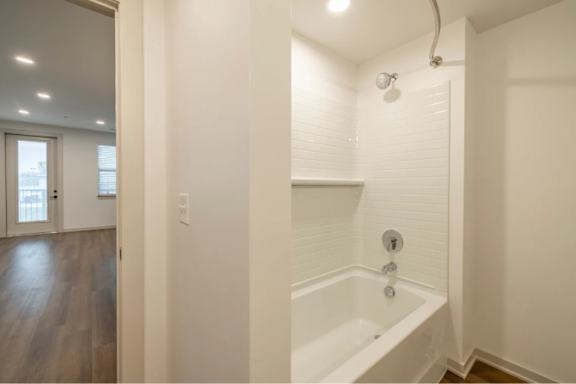 A white bathroom with a tub and a door.