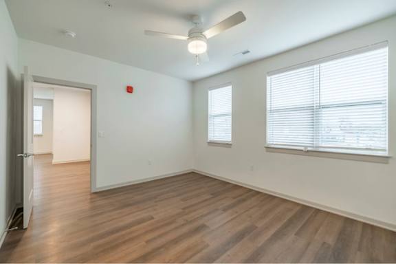 A room with a ceiling fan and wooden flooring.