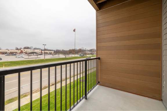 A balcony with a black railing and a wooden wall.