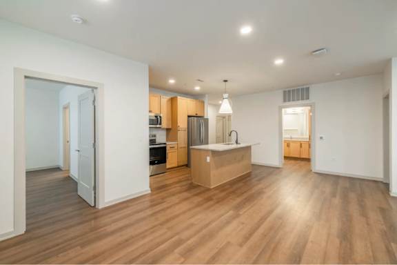 A kitchen with wooden floors and a white wall.