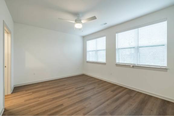 A room with wooden floors and two windows.