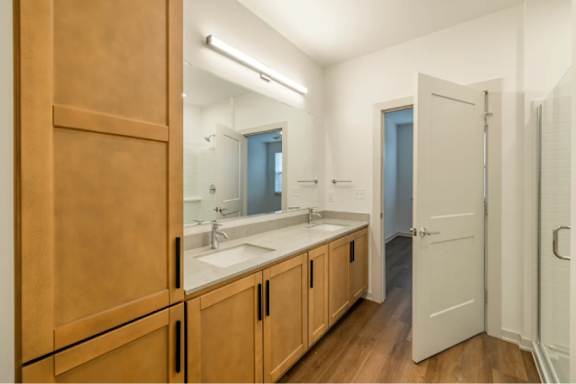 A bathroom with a sink, mirror, and wooden cabinets.