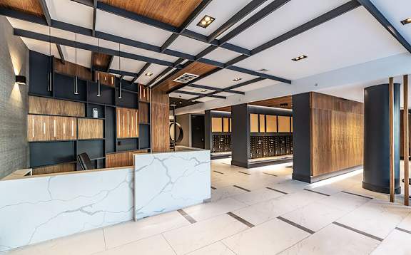 Modern lobby with marble reception desk and wood accents at 1134 Fulton Street Apartments, Brooklyn, NY