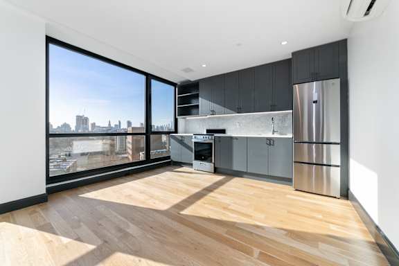 Modern kitchen with large windows and city views at 1134 Fulton Street Apartments, New York