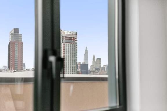 A cityscape is visible through a window with a black frame.