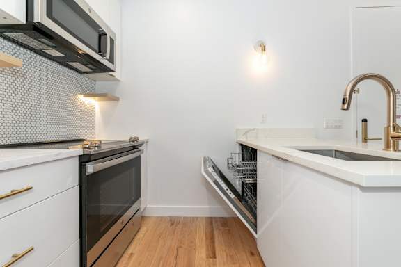 A modern kitchen with a white countertop and stainless steel appliances.