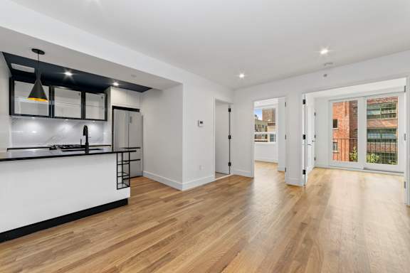 A spacious room with wooden floors and white walls.