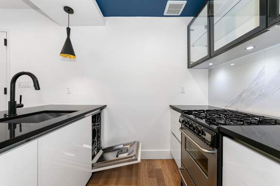 A modern kitchen with black countertops and white cabinets.
