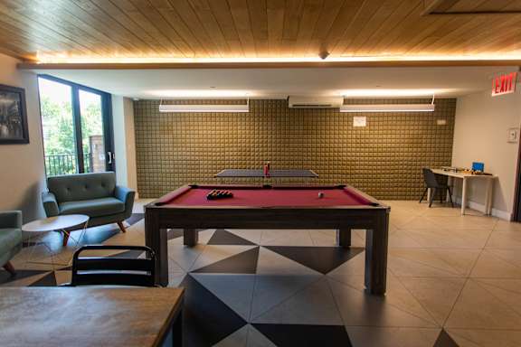 A room with a pool table and a green couch.