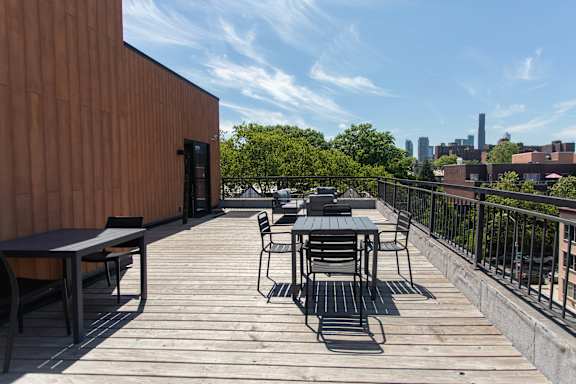 A wooden deck with a table and chairs overlooking a city skyline.