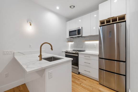 a kitchen with white cabinets and a stainless steel refrigerator