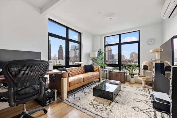 an open living room with a couch and a desk with a large window