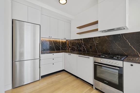 White kitchen with marble backsplash and stainless appliances at 260 Gold Apartments, Brooklyn, 11201