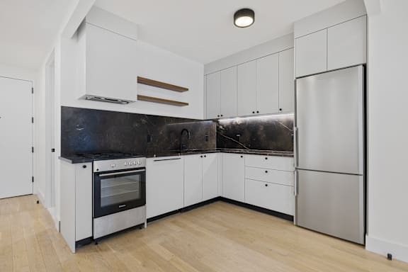 Contemporary kitchen with stainless steel appliances and light wood flooring at 260 Gold Apartments, Brooklyn