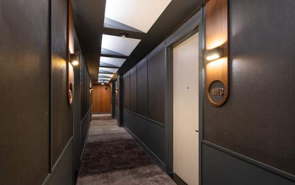 a long hallway with dark wood walls and white doors