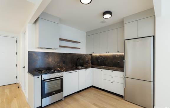 a kitchen with white cabinets and a stainless steel refrigerator