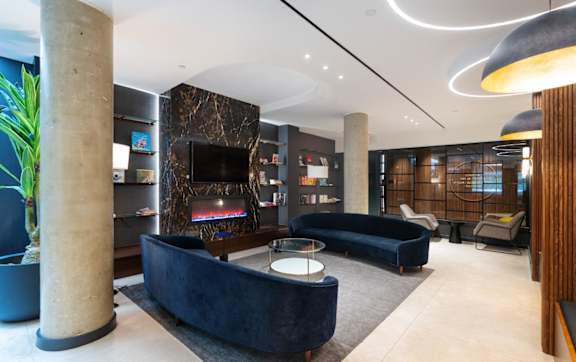 the lobby of a hotel with couches and a fireplace