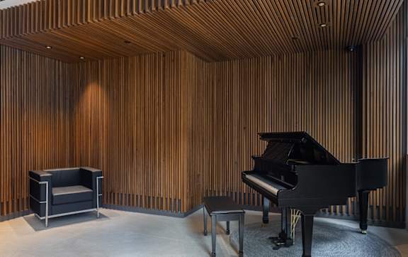 a living room with a piano and a wooden wall