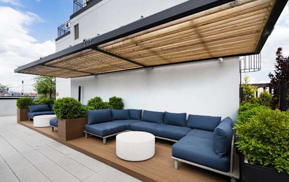 a patio with blue couches and tables and plants