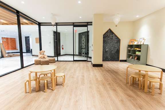 Childrens playroom with wooden tables and chalkboard at 1134 Fulton Street Apartments, New York