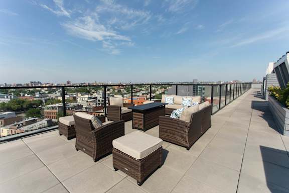 Rooftop terrace with lounge seating and city skyline views at 1134 Fulton Street Apartments, Brooklyn, New York