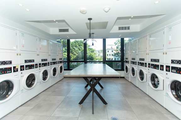 Modern laundry room with front load washers and folding table at 1134 Fulton Street Apartments, Brooklyn, NY 11216