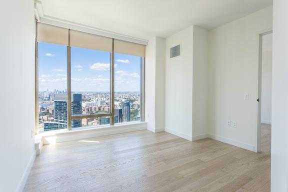 A large empty room with a view of the cityscape outside the window.
