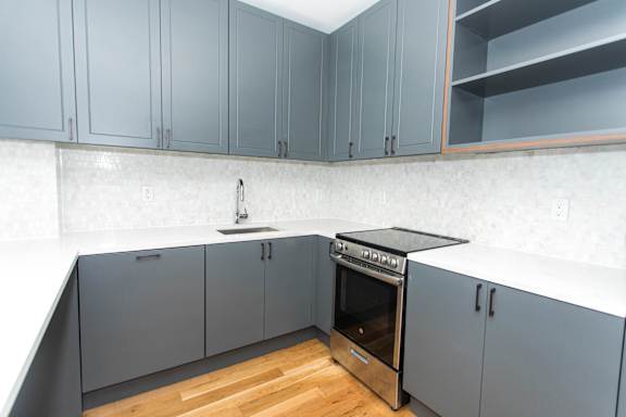 Corner kitchen with stainless steel range and dark countertops at 1134 Fulton Street Apartments, New York