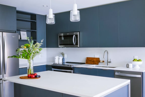 a kitchen with blue cabinets and a white counter top at The Lively, Jersey City, 07302