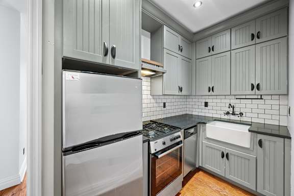 A kitchen with a stainless steel refrigerator and a white sink.