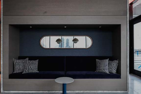 a living room with a blue couch with pillows and a table at The Lively, Jersey City, NJ 07302