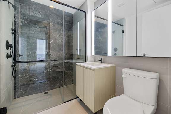 A white toilet sits next to a sink in a modern bathroom.