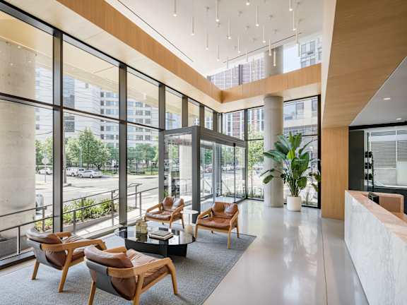 a lobby with chairs and a table in a building with large windows at The Lively, Jersey City