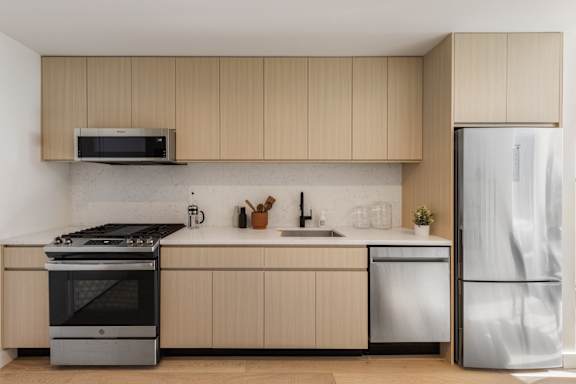 A modern kitchen with a stove, sink, and refrigerator.