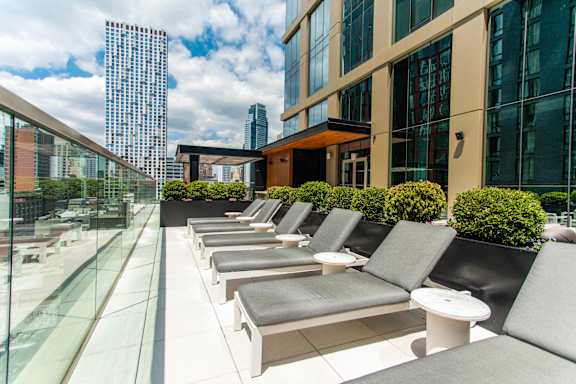 A row of sun loungers are on a terrace with a view of the city.