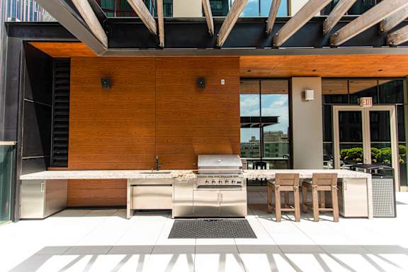 A modern outdoor kitchen with a grill and seating area.