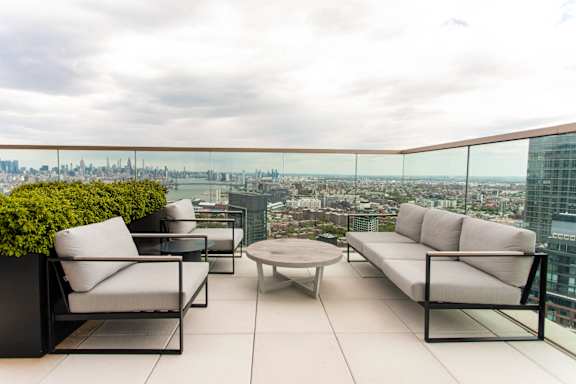 A patio with white furniture overlooking a city.
