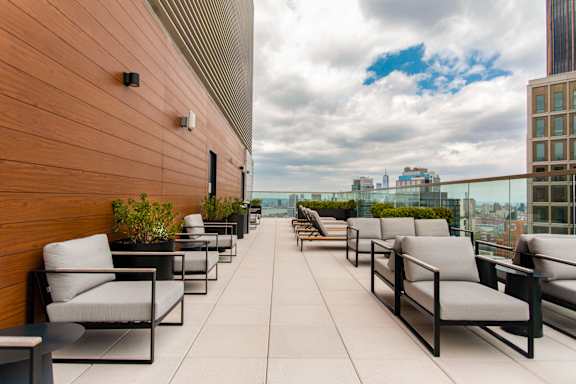 A patio with chairs and a table with a view of the city.