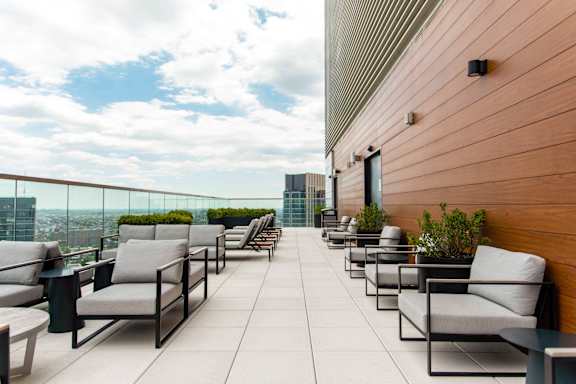 A patio with chairs and tables overlooking a cityscape.