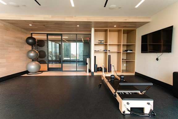 A gym with a rowing machine, weights and a television.