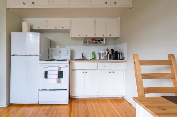 a kitchen with white appliances and a wooden table