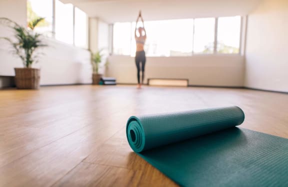 a yoga mat in a yoga room with a woman doing yoga in the background