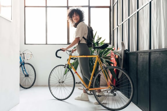 a woman standing next to a yellow bike with a potted plant