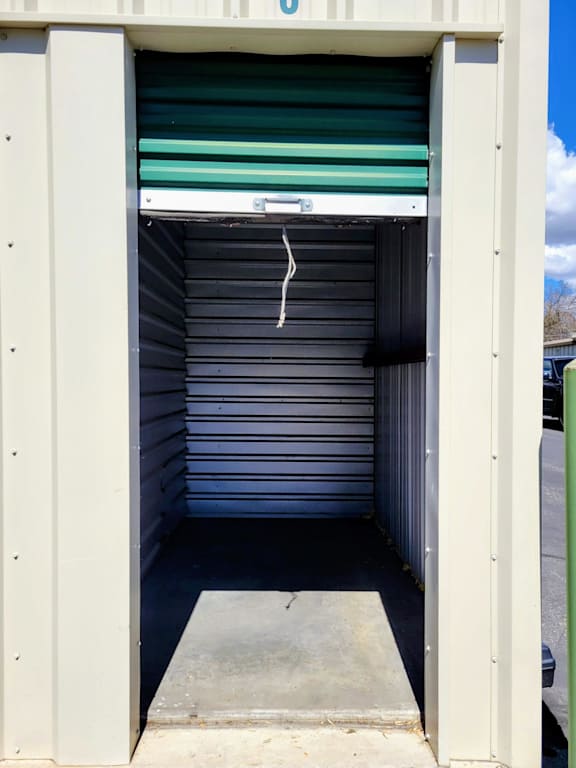 A storage unit with a closed green door and a white door handle.