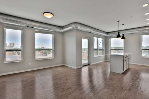 A spacious room with wooden floors and large windows.