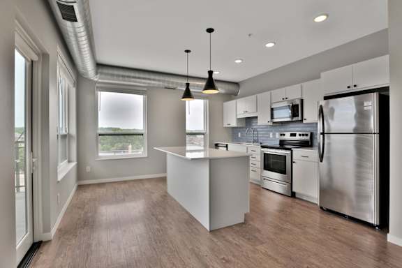 A modern kitchen with stainless steel appliances and wooden flooring.