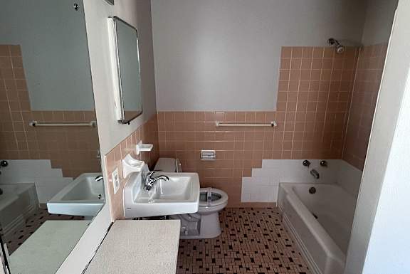 A bathroom with a white sink and brown tiles.