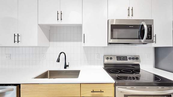 A modern kitchen with a stove, sink, and cabinets.