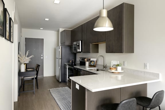 a kitchen and dining area with a white counter top and stainless steel appliances