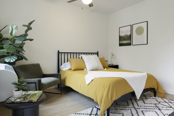 a bedroom with a bed and a chair and a potted plant